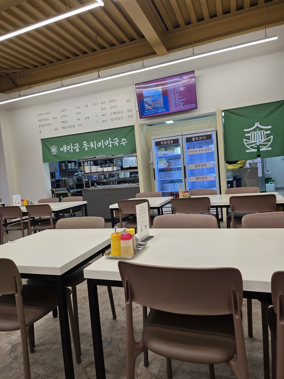 애막골 동치미막국수 주방 위 벽 메뉴판과 셀프코너 냉장고
