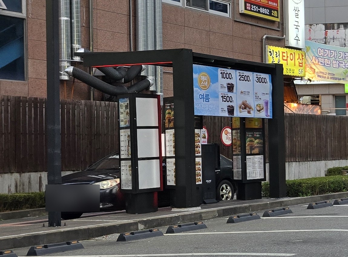 맥드라이브 진입로에 세워진 기둥형 메뉴판과 여름 시즌 한정 간식 안내판