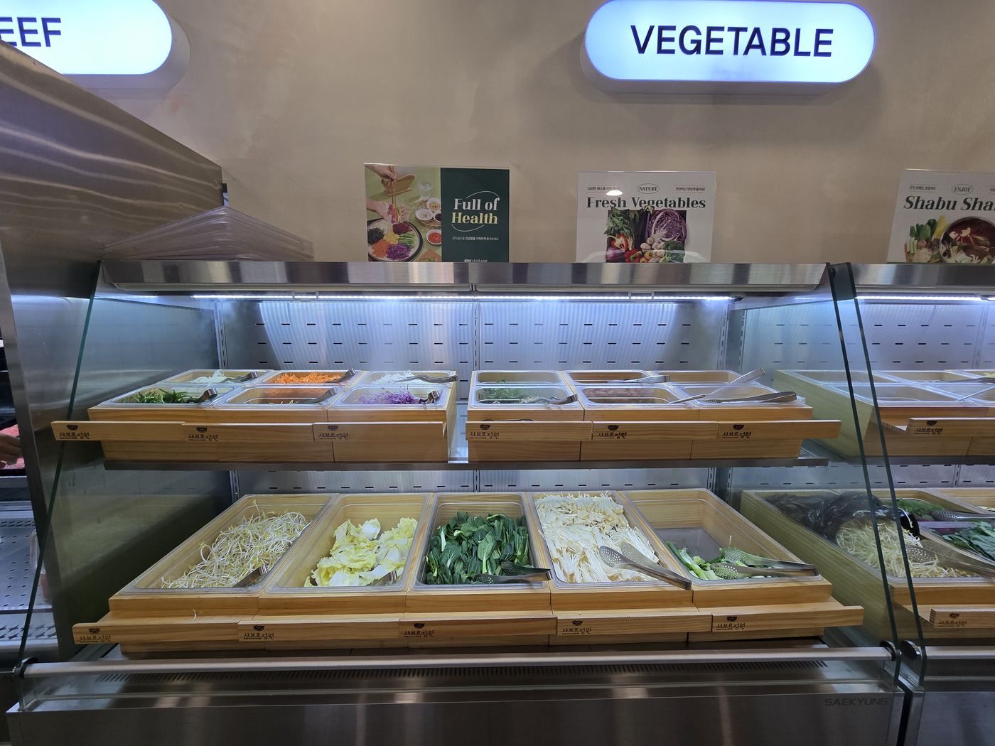 「VEGETABLE」 표시가 달린 냉장 진열대에 숙주, 알배추, 청경채, 팽이버섯, 대파가 담긴 칸