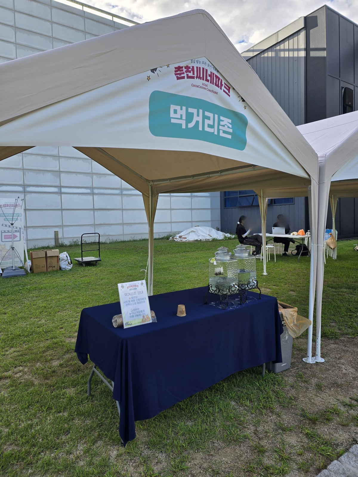 먹거리존이라고 적힌 흰 천막과 물통이 놓인 테이블
