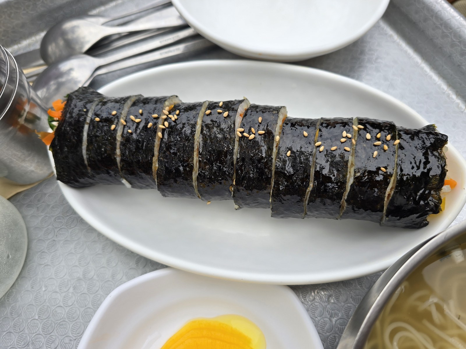 통으로 나온 김밥 한 줄에 깨가 뿌려진 접시